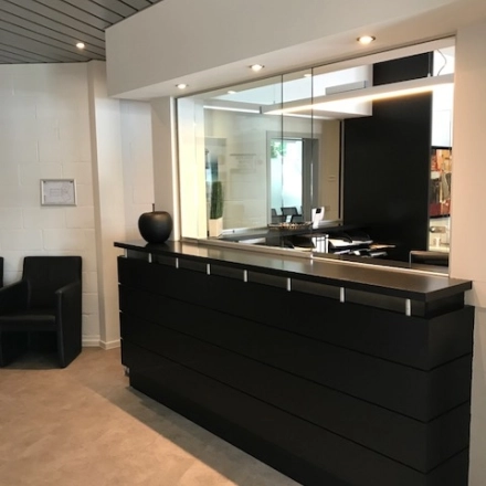 Reception area at De Regenboog 11 in Mechelen North, ideal for office space rental with a sleek desk and modern decor.