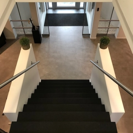 Bright office entrance with modern staircase at De Regenboog 11, ideal for office space rental in Mechelen North.