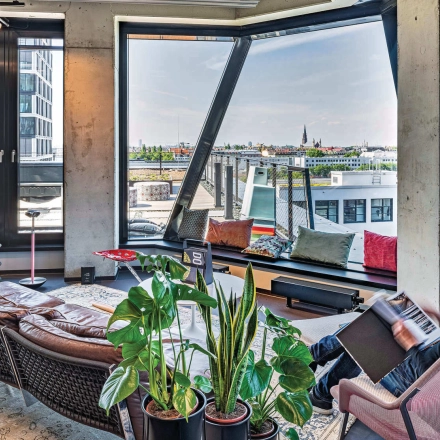 Bright, furnished office space at Rosenheimer Straße 143C, München Werksviertel, featuring large windows with a city view and a person reading.