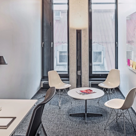 Bright office space for rent at Rosenheimer Straße 143C, München Werksviertel, featuring a meeting area with chairs and a desk with a lamp.