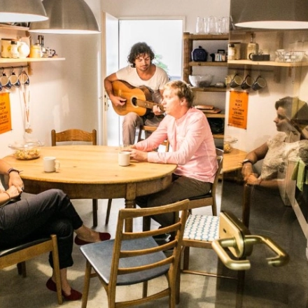 Cozy furnished office space at Werinherstraße 3, Munich Giesing, featuring a kitchen area with employees enjoying coffee and a colleague playing the guitar. Ideal for office space rental.