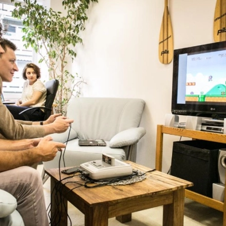 Three people relaxing and playing video games in a furnished office lounge area at Werinherstraße 3, Munich Giesing, featuring a TV and beanbag chairs. Ideal for office space rental.