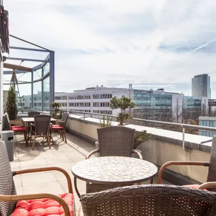 Sunny rooftop terrace with tables and chairs, ideal for breaks at this office space rental in Munich Laim.