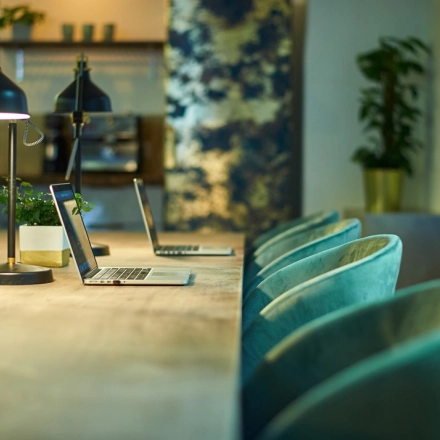 Cozy office space rental at Amalienstraße 71, Munich Maxvorstadt, featuring a long table, chairs, and laptops, perfect for collaborative work.
