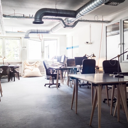 Modern office space at Blütenstraße 15 in Munich Maxvorstadt featuring desks and computers under industrial-style ductwork, ideal for teams seeking office space rental.