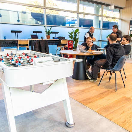 Modern office space at Oskar-von-Miller-Ring 20 in Munich Maxvorstadt, featuring a game table and a group of professionals engaged in a meeting. Ideal for those seeking office space rental.