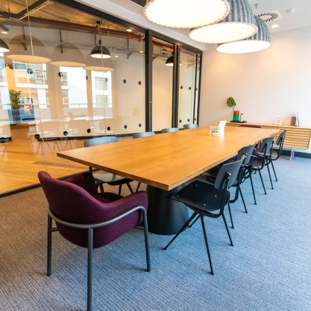Spacious office to rent at Oskar-von-Miller-Ring 20, Munich Maxvorstadt, featuring a modern conference room with a large wooden table, black chairs, and decorative lighting, perfect for office space rental.