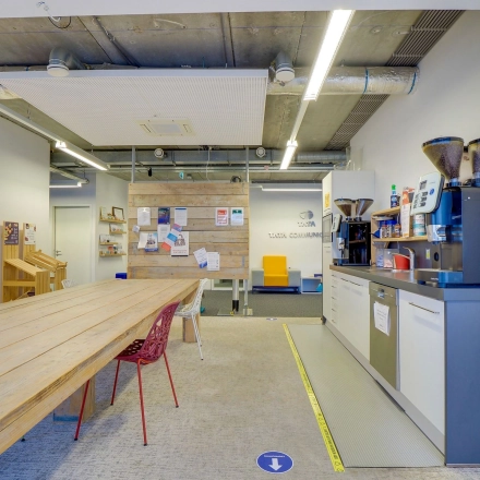 Interior workspace at Zoomstede 19, Nieuwegein features a long wooden table, coffee machines, and bulletin boards, perfect for creative brainstorming. Ideal for office space rental.