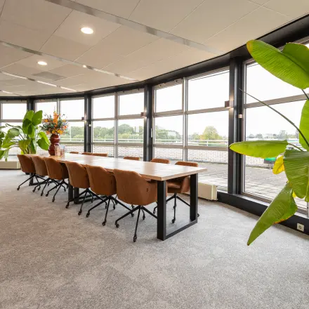 A furnished office space at Patroonstraat 13, Nijkerk, featuring large windows and modern furniture. Ideal for those looking for office space rental with natural light and contemporary design.