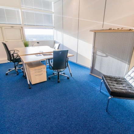 Bright office space in Nijmegen with a central desk and chairs, perfect for businesses seeking office space rental. The well-lit area offers a comfortable setting with modern furnishings.