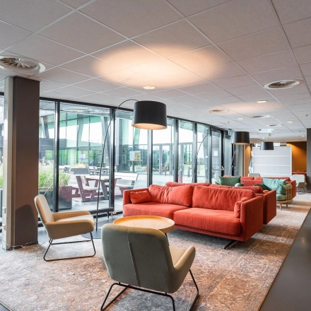 Modern office space for rent at Jonkerbosplein 52 in Nijmegen featuring a stylish lounge area with comfortable seating and large windows.