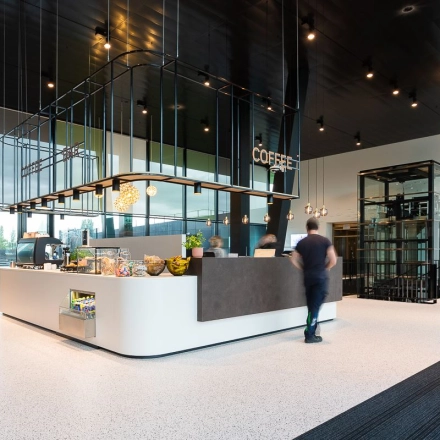 Modern office interior at Jonkerbosplein 52 in Nijmegen featuring a stylish coffee bar with people engaged in business activities, ideal for office space rental.