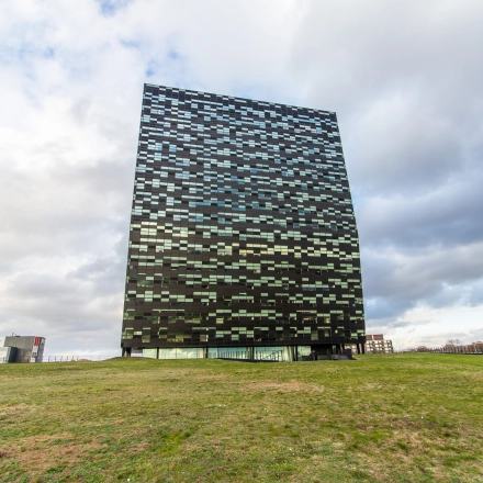 Exterior view of the modern office building for rent at Jonkerbosplein 52, Nijmegen, featuring a checkerboard facade and surrounding green space.