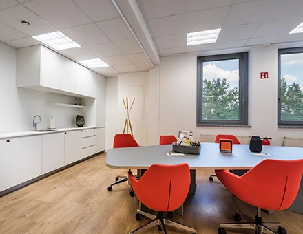 Bright office space at Südwestpark 67, Nürnberg Röthenbach featuring modern furnishings and red chairs around a meeting table, ideal for office space rental.