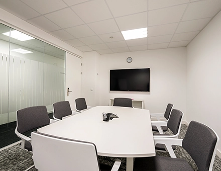 A furnished meeting room in an office to rent at Südwestpark 67, Nürnberg Röthenbach, featuring a long table, chairs, and a TV on the wall.
