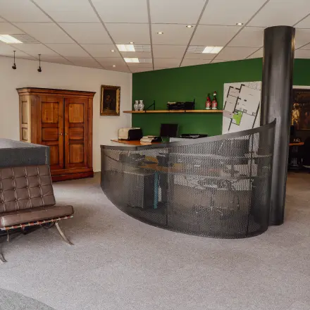 Furnished workspaces with a modern reception desk, green feature wall, and a blend of classic and contemporary furnishings at Abdis van Thornstraat 74, ideal for office space rental.