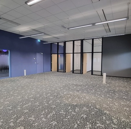 Spacious office to rent at Veengang 1, Oosterwolde, featuring patterned carpet, large windows, and ample natural light.