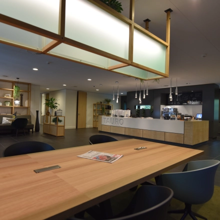 Spacious and modern office space with wooden tables, chairs, and plants at Laan van Vredenoord 33, ideal for office space rental.
