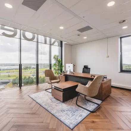 Bright office space with large windows, a view of Rijswijk, and modern furnishings including a desk and chairs, ideal for office space rental.
