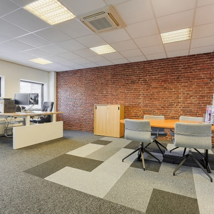 Modern office space at Patrijsweg 62, Rijswijk, featuring contemporary furnishings, a brick accent wall, and ample lighting, ideal for office space rental.