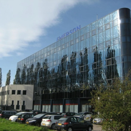 Modern office building with reflective glass facade at Patrijsweg 62, Rijswijk, surrounded by trees and a parking area. Ideal for office space rental.