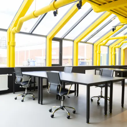 Bright office space with yellow beams and large windows at Volmerlaan 7, Rijswijk, ideal for those seeking office space rental.
