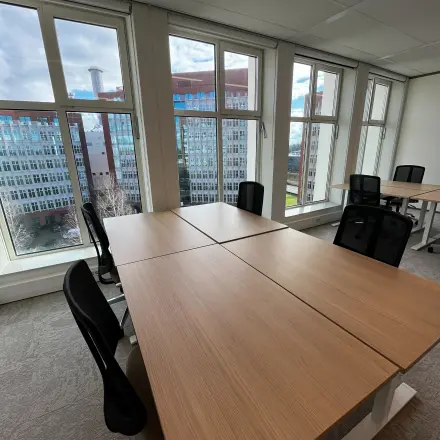 Bright office space with large windows overlooking Rotterdam Alexander, furnished with desks and chairs, ideal for office space rental.