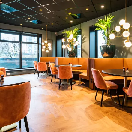 Stylish office space at Rotterdam Alexander with elegant seating and decor, ideal for rental. Large windows provide natural light.