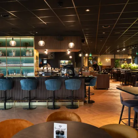 Elegantly furnished office lounge with bar seating and lush green plants at George Hintzenweg 77-89, ideal for rent office space in Rotterdam Alexander.