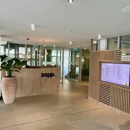 Reception area at Bahialaan 100, Rotterdam Brainpark with a modern design, ideal for office space rental featuring a sleek desk and digital display.