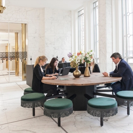 Office space rental at Blaak 34, Rotterdam Center, featuring a round table with people working on laptops.