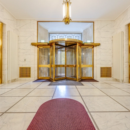 Spacious office entrance at Blaak 34 in Rotterdam Center, ideal for office space rental with its elegant design and revolving doors.