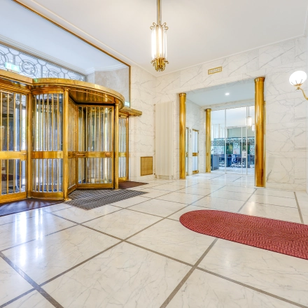 Spacious entrance area of an office to rent at Blaak 34, Rotterdam Center, featuring elegant marble detailing and a vintage revolving door. Ideal for office space rental with welcoming aesthetics.
