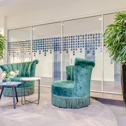 Furnished seating area with green chairs and plants at the office to rent at Blaak 34, Rotterdam Center, ideal for relaxed discussions.