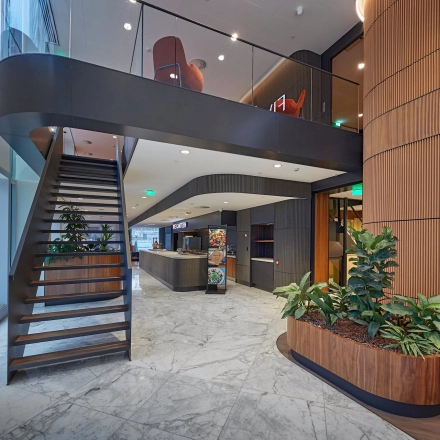 Modern office interior at Blaak 555, Rotterdam Center featuring a sleek staircase, natural lighting, and stylish planter boxes, ideal for office space rental.