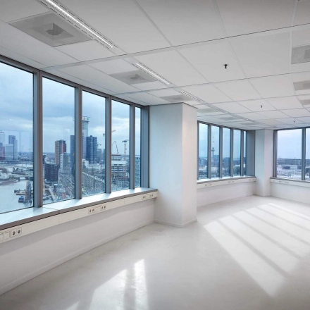Bright, unfurnished office space at Blaak 555 in Rotterdam Center, featuring large windows with city views, ideal for office space rental.