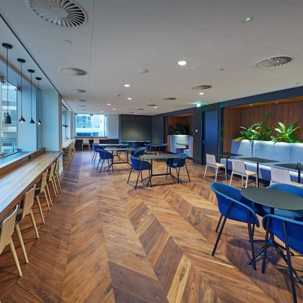 Spacious office in Blaak 555, Rotterdam Center, featuring modern workspaces with blue seating, wood flooring, and large windows ideal for office space rental.