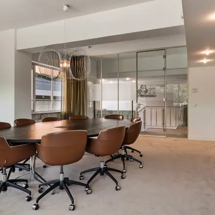 Spacious conference room at Coolsingel 104, Rotterdam Center, featuring a large oval table with comfortable chairs, ideal for office space rental.