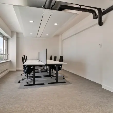 Bright office space at Coolsingel 104 in Rotterdam Center featuring rows of desks and chairs ideal for office space rental.
