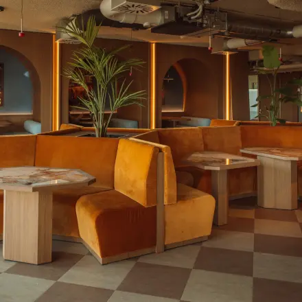 Stylish office space to rent at Coolsingel 139, Rotterdam Center, featuring orange booths and wooden tables, ideal for meetings and collaborative work.