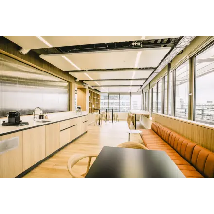 Modern office space with a sleek kitchen area featuring wooden cabinetry and bar seating, located at Coolsingel 65 in Rotterdam Center, perfect for office space rental.