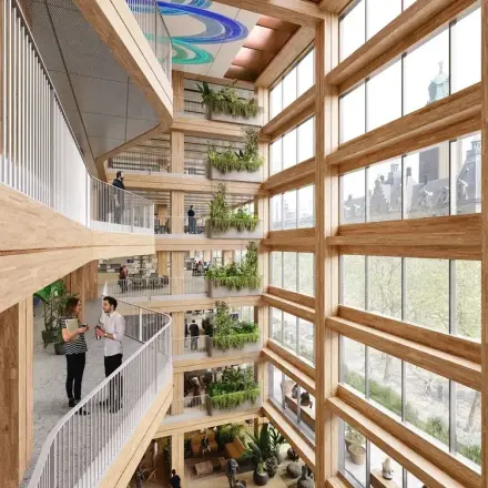 Bright and modern atrium at Coolsingel 75, Rotterdam Center, showcasing multiple floors of office space rental. People are engaged in conversation at balconies, surrounded by greenery and natural light.