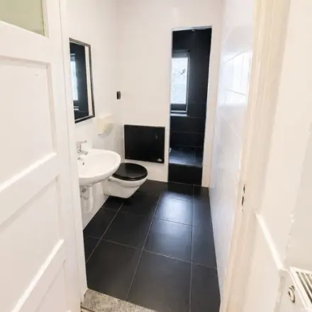 Office restroom at Mauritsweg 33 A01 in Rotterdam Center, featuring modern fixtures and sleek black and white tiling, available for office space rental.