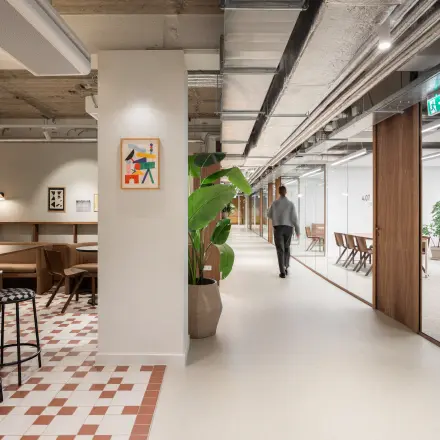 Modern office space at Stadhuisplein 9-23, Rotterdam Center with a sleek design, featuring a mix of wooden furniture and contemporary decor. A person is walking through the hallway.