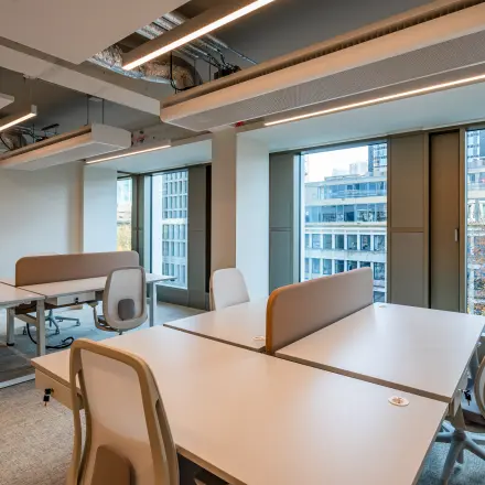 Bright modern office space at Stadhuisplein 9-23 in Rotterdam Center featuring large windows and contemporary furniture.