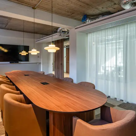 Modern conference room with a long wooden table, cushioned chairs, and a mounted TV at the office space rental in Rotterdam Center.