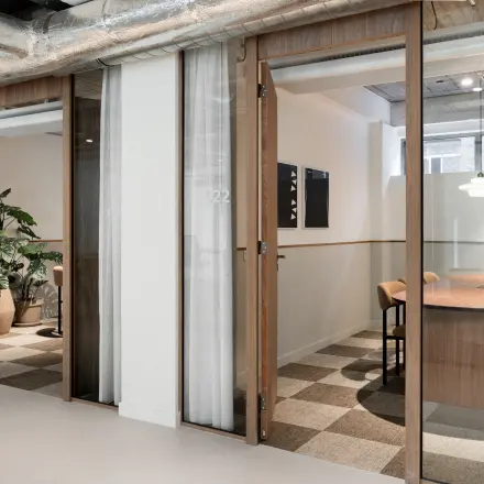Modern office to rent at Stadhuisplein 9-23, Rotterdam Center, featuring glass-walled workspaces and stylish furnishings, ideal for productive meetings and collaborations.