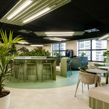 Modern furnished office space for rent at Weena 335, Rotterdam Center, featuring sleek tables and lush plants, ideal for workspaces.