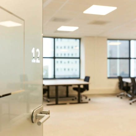 Bright office space for rent at Weena 335, Rotterdam Center, featuring desks, chairs, and large windows that offer natural light, ideal for productive work.