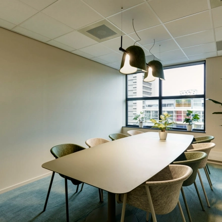 Bright conference room available for office space rental at Weena 335 in Rotterdam Center, featuring a large table, modern chairs, and stylish lighting, perfect for collaborative meetings.